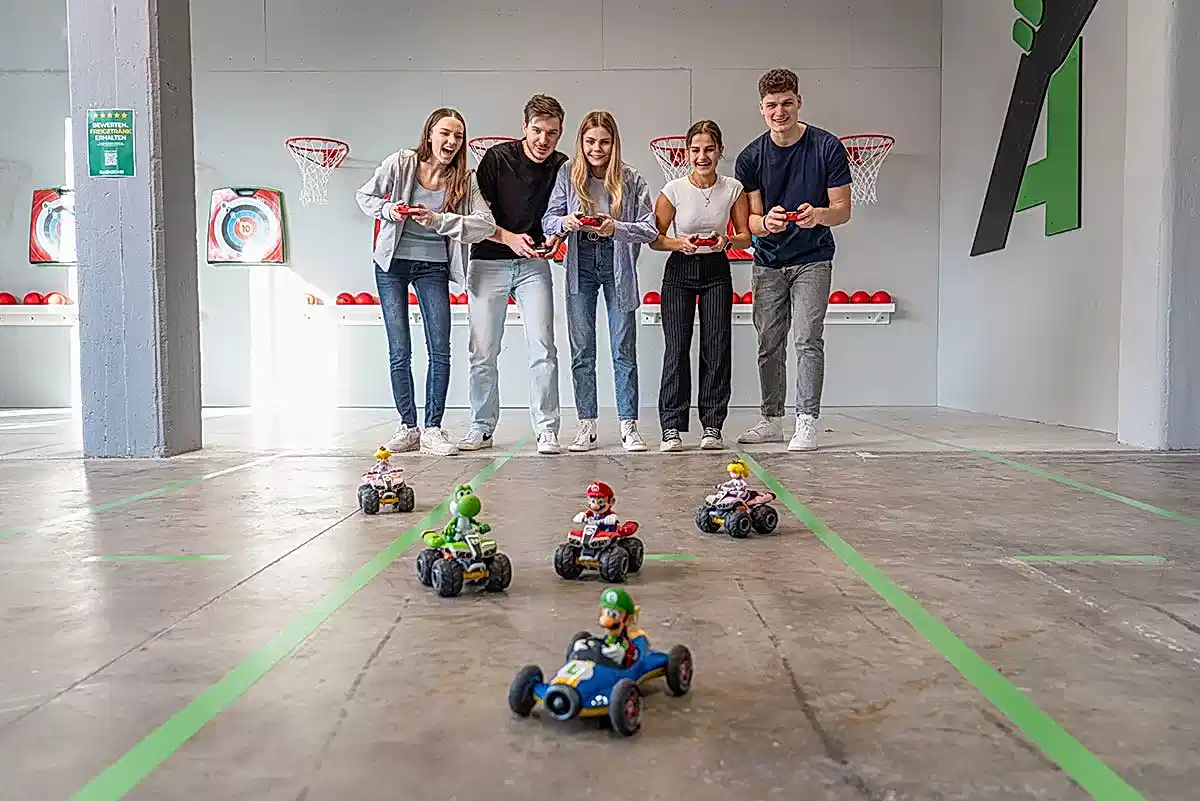 teilnehmende steuern ferngesteuerte autos bei einem spannenden wettkampf im indoor parcours.